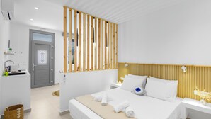 Ein modernes Hotelzimmer mit einem großen Bett, einem Holzkopfteil, weißen Wänden und einem kleinen Nachttisch mit einer Blumenvase.