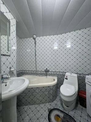 A bathroom with a sink, bathtub, toilet, and a mirror.