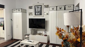 A living room with a TV, cabinets, a coffee table, and a decorative plant. - Beautiful air-conditioned apartment a few meters from the center and tram stop. (Firenze)