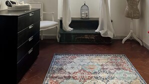 A room with a black dresser, a white chair, a patterned rug, a mannequin, and sheer curtains over a window. - Beautiful air-conditioned apartment a few meters from the center and tram stop. (Firenze)