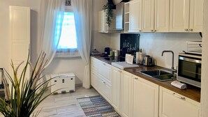 A kitchen with white cabinets, a wooden countertop, a sink, a stove, and a window with sheer curtains. - Beautiful air-conditioned apartment a few meters from the center and tram stop. (Firenze)