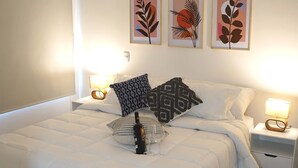 A neatly made bed with white bedding, two bedside tables with lamps, and three framed artworks on the wall. - Luxury Entire 2 BR Condo Oceanfront In Cartagena (Cartagena)