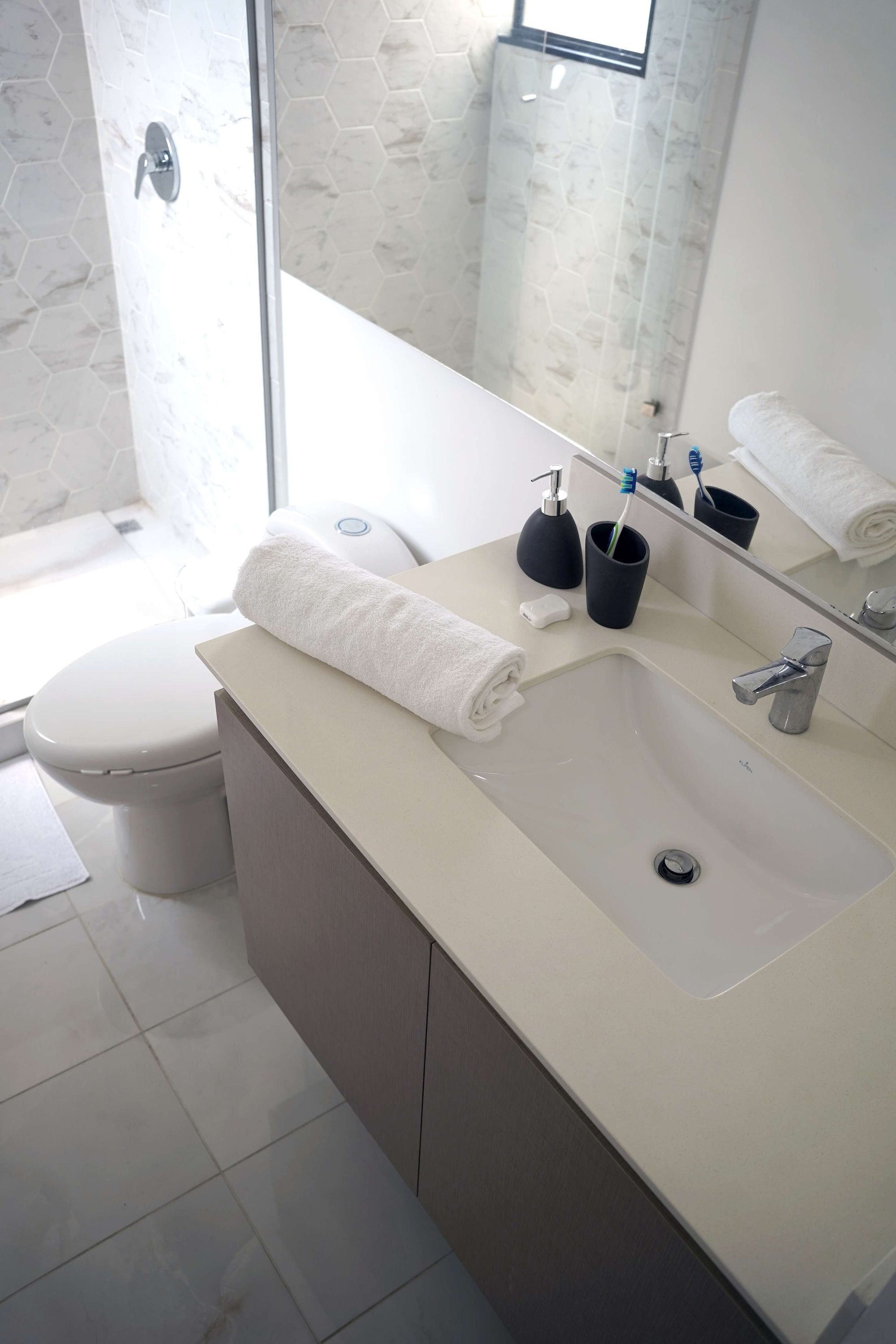 A modern bathroom with a white toilet, a beige sink, and a glass shower enclosure.