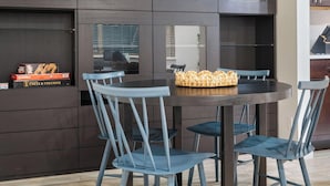 A modern kitchen with dark cabinetry, a round dining table, and blue chairs. - East Side #212 xxxxxxx (Austin)