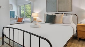 A bedroom with a bed, bedside tables, a nightstand, and a window with blinds. - East Side #212 xxxxxxx (Austin)