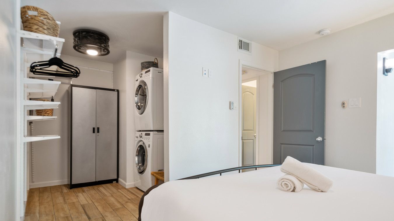 Un dormitorio con cama, armario, lavadora y puerta.