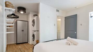 Un dormitorio con cama, armario, lavadora y puerta.