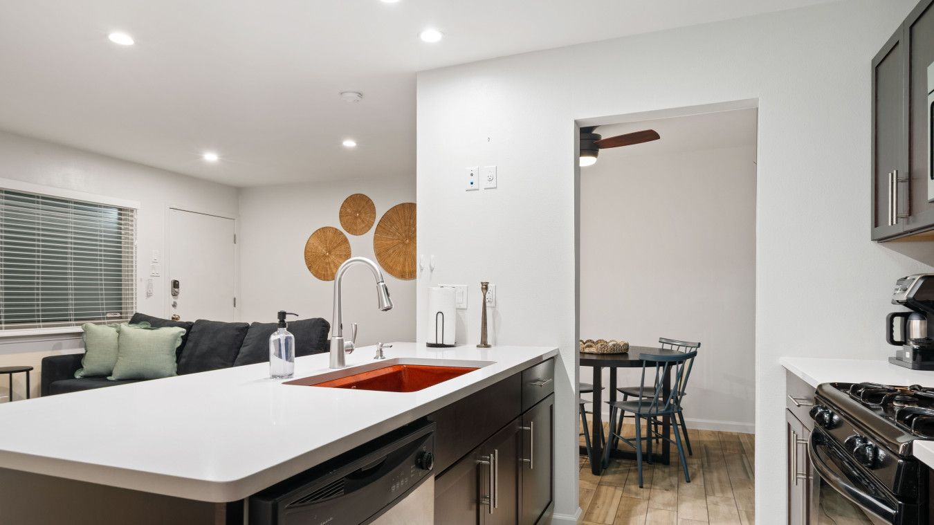 A modern kitchen with a central island, stainless steel appliances, and a dining area with a table and chairs.