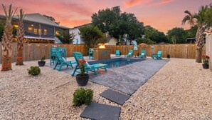 Un jardin avec une piscine, du mobilier d’extérieur et une clôture en bois.