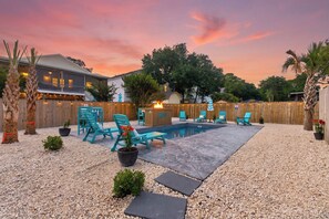 Un patio trasero con piscina, mobiliario exterior y valla de madera.