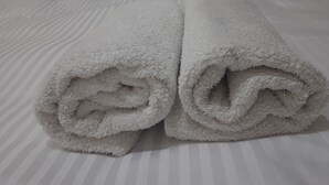 Una cama bien hecha con almohadas a rayas y toallas blancas enrolladas.