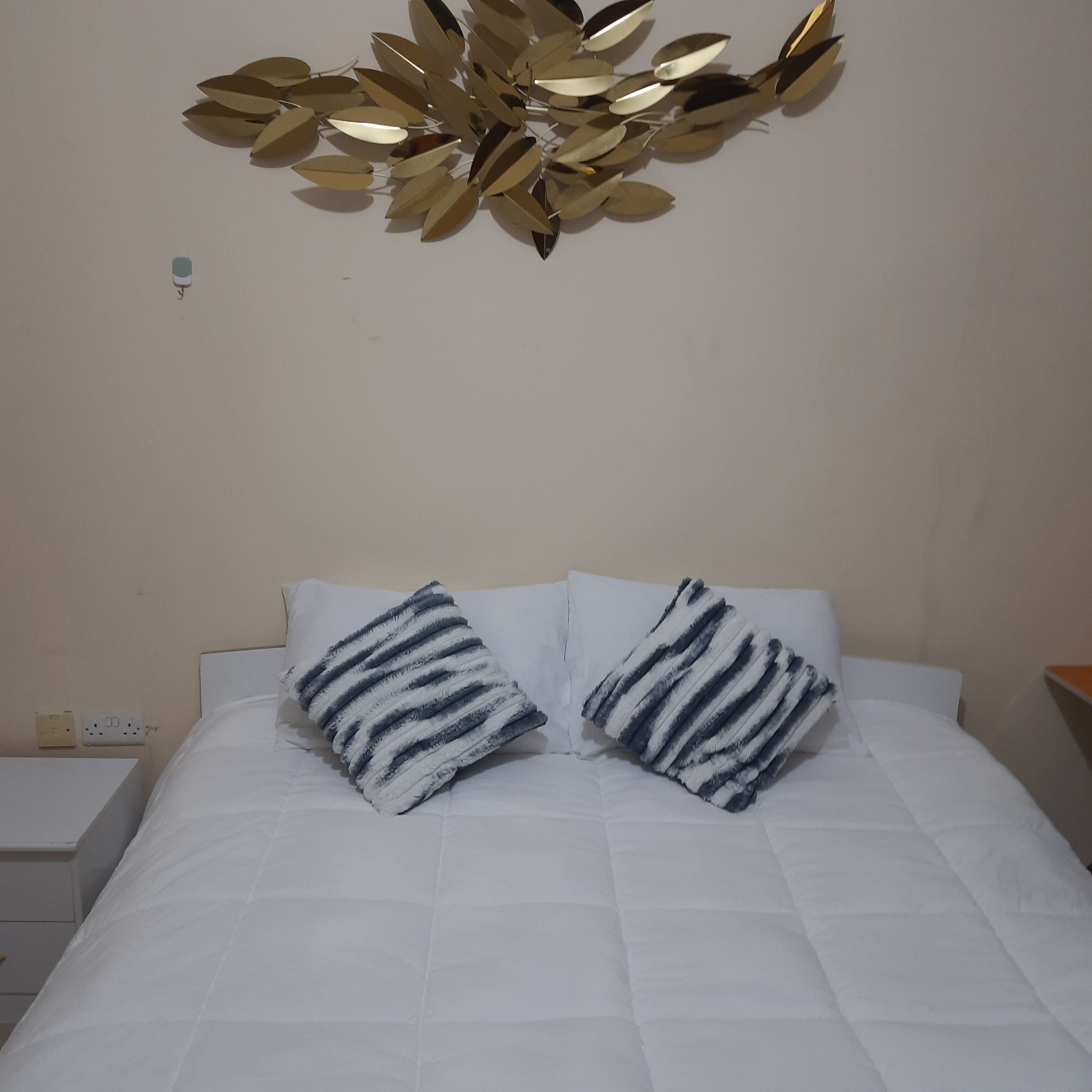 Ein Bett mit weißer Bettwäsche und zwei gestreiften Kissen.