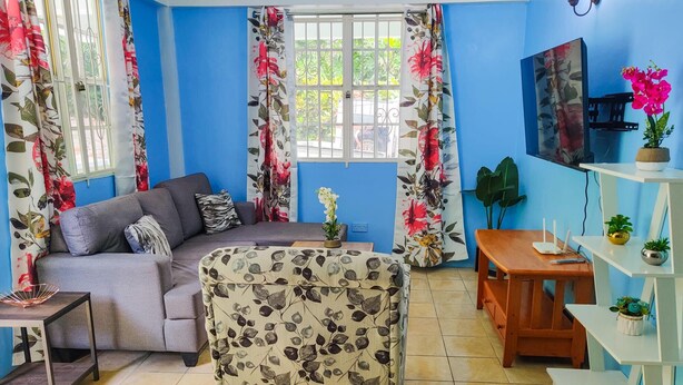 Un salon avec un canapé, une table basse et un téléviseur fixé au mur.