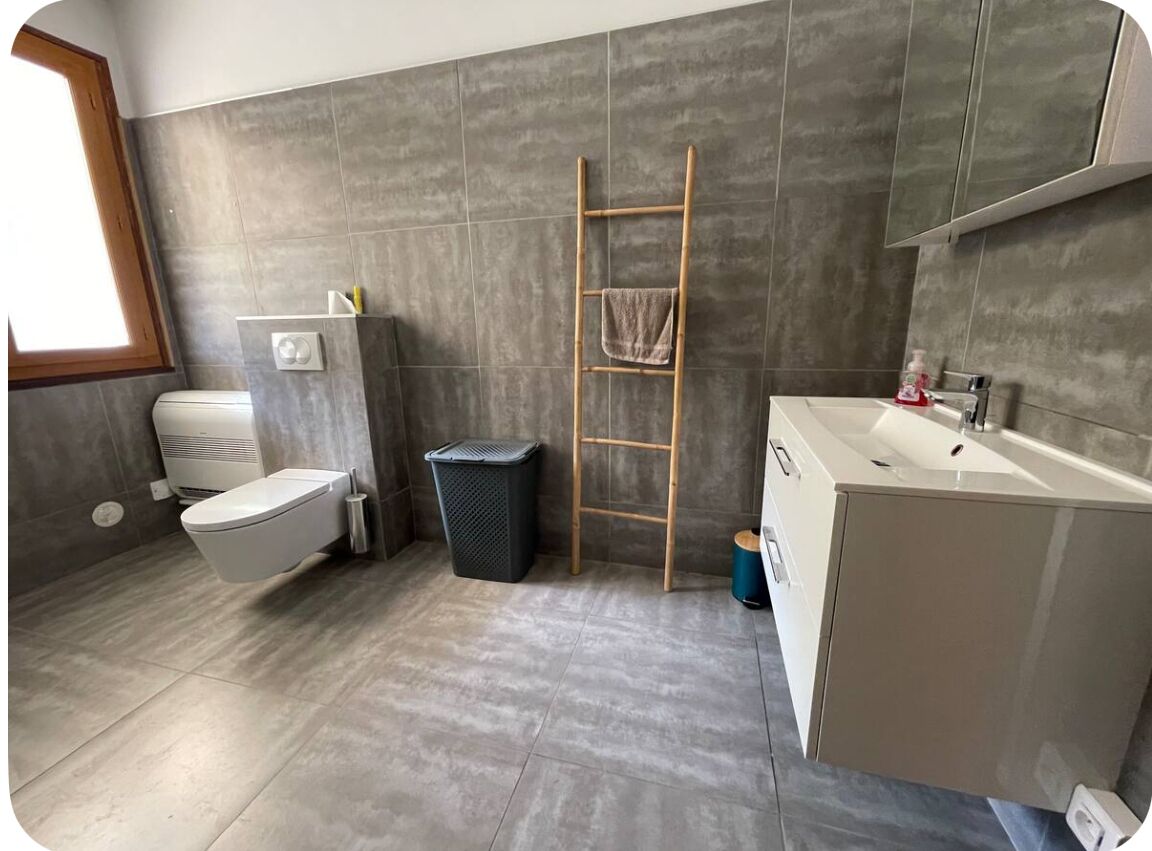 Moderni kylpyhuone, jossa on wc, pesuallas ja suihkutila.