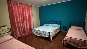 A room with two single beds, a ceiling fan, and a red curtain. - Mansion of the Valentines (Napoli)