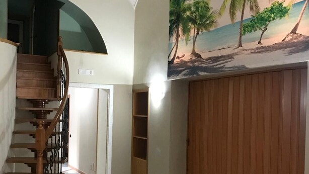 A spacious room with a tiled floor, a wooden staircase, and a mural of a beach scene on the wall. - Mansion of the Valentines (Napoli)