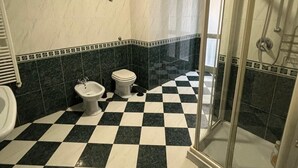 A bathroom with a checkered floor, a toilet, a bidet, and a glass-enclosed shower area. - Mansion of the Valentines (Napoli)