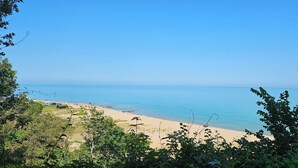 Een strand met helderblauw water, een zandstrand en omliggende begroeiing.
