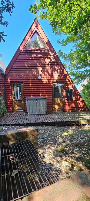 A red wooden house with a triangular roof, a wooden door, and a window.