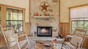 Un intérieur chaleureux avec une cheminée en pierre, des meubles en bois et de grandes fenêtres.