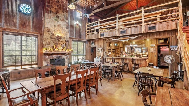 Un intérieur rustique avec des tables et des chaises en bois, une cheminée en pierre et un coin bar.