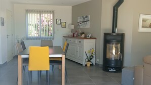 A modern living room with a dining area, a fireplace, and a kitchen in the background.