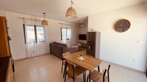 A modern kitchen with a dining table, chairs, a refrigerator, and a clock on the wall. - ALIZEA apartment, spacious with large terrace (Saint-Pierre)