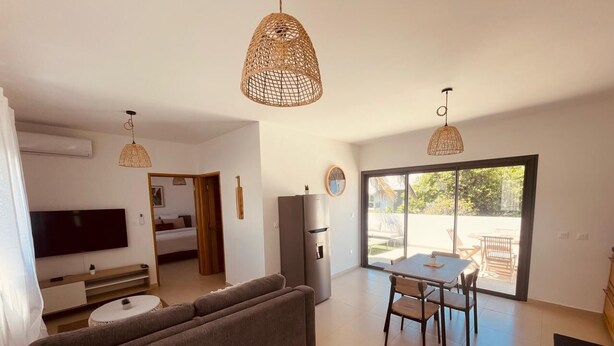 A modern living room with a sofa, TV, and dining area with chairs and a table. - ALIZEA apartment, spacious with large terrace (Saint-Pierre)