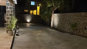 A paved courtyard with a stone wall and a palm tree. - ALIZEA apartment, spacious with large terrace (Saint-Pierre)