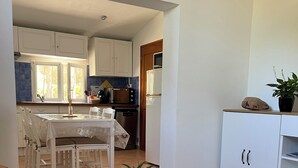 A modern kitchen with white cabinets, a dining area with a wooden table and chairs, and a potted plant on the table. - T2 apartment in condominium (Villa) with pool access (Fréjus)