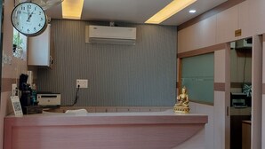 A reception area with a clock, air conditioning unit, and a Buddha statue. - Hotel Pravas Inn (Lucknow)