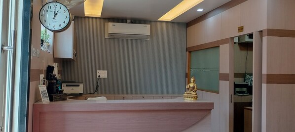 A reception area with a clock, air conditioning unit, and a Buddha statue. - Hotel Pravas Inn (Lucknow)