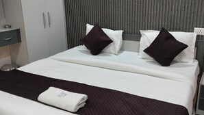 A modern hotel room with a bed, a wardrobe, and a wall with vertical lines. - Hotel Pravas Inn (Lucknow)