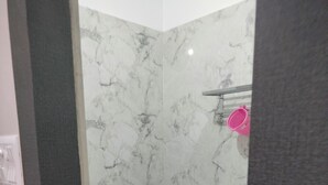 A bathroom with a toilet, bidet, and a marble wall. - Hotel Pravas Inn (Lucknow)