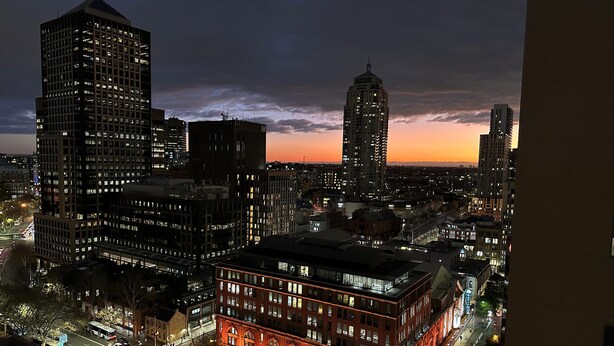 A nighttime cityscape with illuminated buildings and a prominent red-lit building in the foreground.
