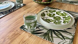 Et spisebord dækket med tallerkener, glas og en skål med frugt.