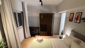 A hotel room with a large bed, a desk, a chair, a wardrobe, and a potted plant. - The Ground-floor Gem - Zahraa Al Maadi (Cairo Governorate)