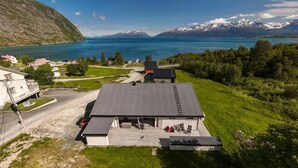 A lakeside property with a large building, a dock, and a view of mountains and a lake. - Lyngen Aurora House (Lyngseidet)