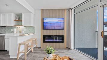 Una cocina moderna con televisor integrado, taburetes de bar de madera y una planta en maceta sobre una bandeja de madera.