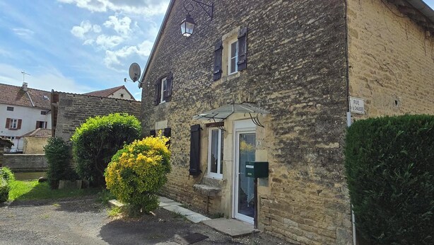 A stone building with a small garden, a satellite dish, and a door with a number.