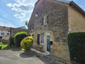 Un bâtiment en pierre avec un petit jardin, une antenne parabolique et une porte portant un numéro.