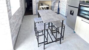 A compact kitchen with a stone wall backsplash, a central island with stools, and modern appliances.