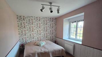 Ein Schlafzimmer mit Bett, Fenster und Heizkörper.