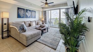 A living room with a sofa, coffee table, and a large potted plant. - Disney Coastal Condo (Orlando)
