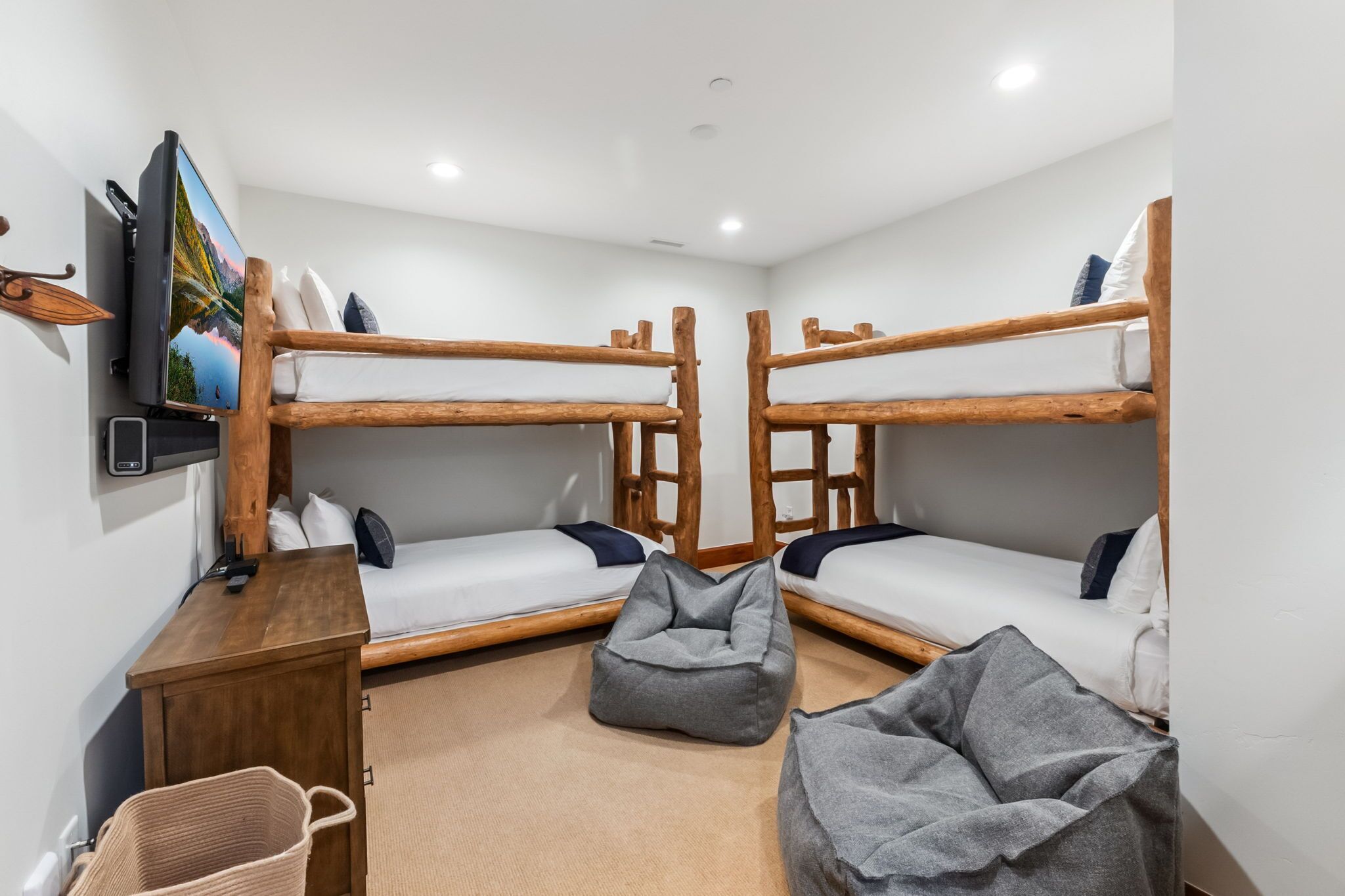 A room with two bunk beds, a television, a desk, and a bean bag chair.