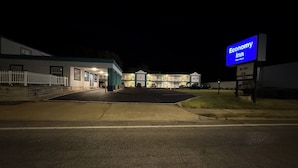 A motel with a signboard, a parking lot, and a building with multiple rooms. - ECONOMY INN (Belleville)