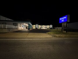 A motel with a parking lot, a signboard, and a building with multiple windows.