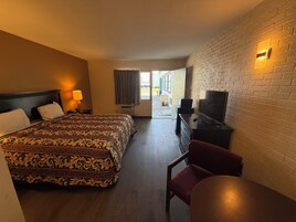 A hotel room with a large bed, a TV, a desk, and a chair.