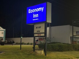 A nighttime view of an Economy Inn sign with a Notary and ATM sign below it.