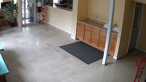 A spacious room with a tiled floor, a small rug, a wooden counter, and a potted plant. - ECONOMY INN (Belleville)